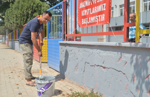 Okul müdürü elinde fırçayla okulu boyuyor