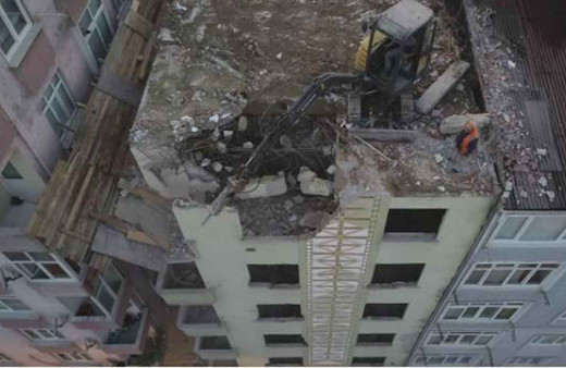 6 katlı riskli bina çatısına çıkarılan iş makinesiyle yıkılıyor
