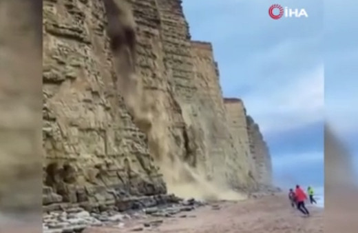 Kumsalda yürürlerken dev kaya parçası üzerlerine doğru geldi! Korku dolu anlar kamerada