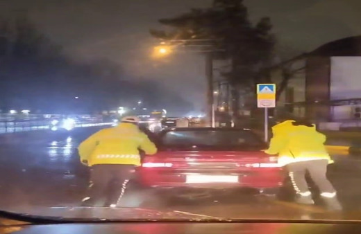 Arızalanan otomobili trafik polisleri yağmurun altında itti